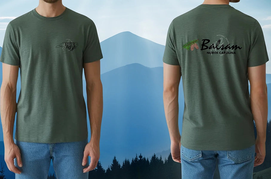 Green t-shirt with logos on front and back worn by a person, with a mountainous landscape in the background.