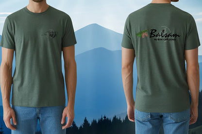 Green t-shirt with logos on front and back worn by a person, with a mountainous landscape in the background.