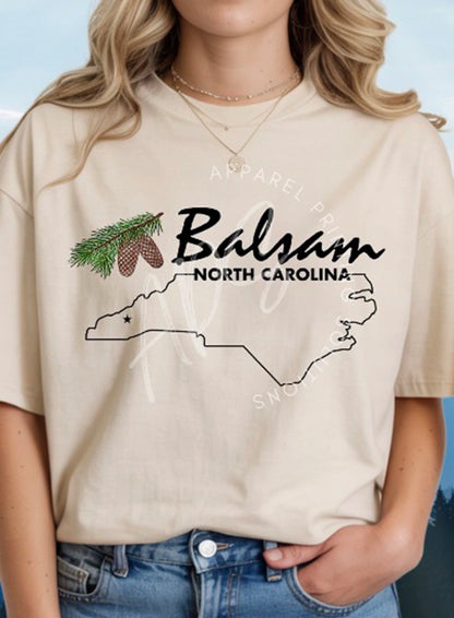 Person wearing a beige t-shirt with 'Balsam North Carolina' design